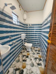 a bathroom with blue and white stripes with a toilet and sink at sundarbon birds view cottage in Japur