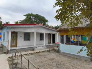 a small white house with a thatch roof at sundarbon birds view cottage in Japur