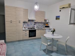a kitchen with a table and a table and chairs at Isola del sole, Appartamenti con piscina in Balestrate