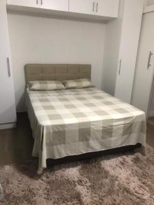 ein Schlafzimmer mit einem Bett mit einer karierten Decke in der Unterkunft Apartamento aconchegante e espaçoso! in Guarujá