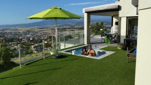 two people sitting in a pool under a green umbrella at Villa Lucca in Cape Town