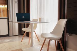 a table with two white chairs and a laptop on it at Lovely 1-bedroom rental unit in downtown in Dushanbe