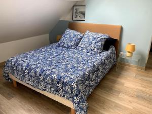 a bedroom with a bed with a blue comforter and pillows at Le petit bois mayetais in Mayet