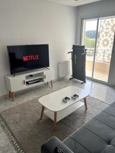 ein Wohnzimmer mit einem TV und einem Sofa in der Unterkunft Cozy Hideaway at Sousse in Port El-Kantaoui