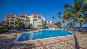 a pool at a resort with palm trees and condos at Confortable vista al mar in Juan Dolio