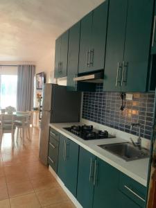 a kitchen with green cabinets and a sink and a refrigerator at Confortable vista al mar in Juan Dolio