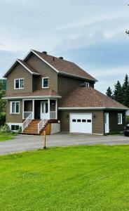 a house with a large driveway with a white garage at Domaine à Blue in Baie-Saint-Paul