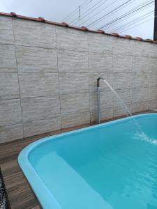 a swimming pool with a water fountain next to a wall at Casa Praia Mongaguá in Mongaguá