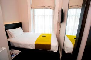 ein kleines Schlafzimmer mit einem Bett und einem Fenster in der Unterkunft Bloomsbury Palace Hotel in London