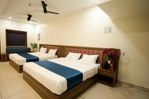 a hotel room with two beds and a tv at Grand View Residency in Nīleshwar