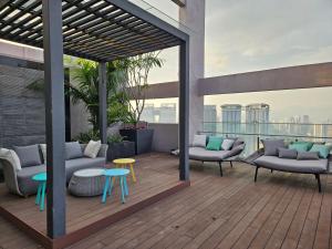 a deck with couches and tables on a building at SerenityStayatRiveria KL Sentral in Kuala Lumpur