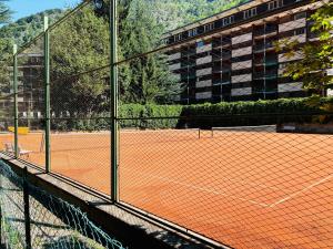 un campo da tennis con rete e un edificio di Studio Piccola Renna a Limone Piemonte