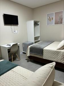 una camera da letto con due letti e una scrivania con un computer di Pousada do Catarina a Paraíso do Sul