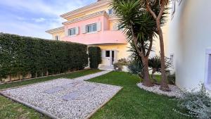 a pink house with a palm tree in the yard at Casa da Amália in Cascais