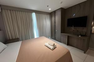 a hotel room with a bed with a television and towels at Brisas do Lago - Apartamento 2 in Brasilia