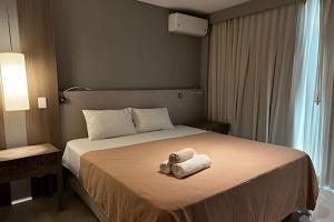 a hotel room with a bed with two towels on it at Brisas do Lago - Apartamento 2 in Brasilia +8 photos