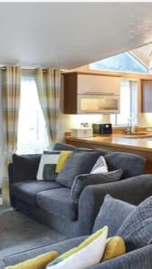 a living room with a blue couch and a kitchen at Woodland Lodge in Plumbland