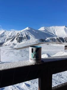 a coffee cup sitting on a rail with snow covered mountains at Chalet Gudauri in Gudauri