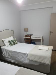 a bedroom with a white bed with a desk and a chair at Beira Mar Loft in Aveiro