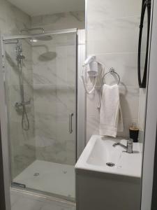 a white bathroom with a shower and a sink at Beira Mar Loft in Aveiro