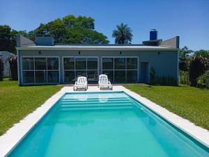 a house with a swimming pool and two chairs at Quincho El Solar in Corrientes