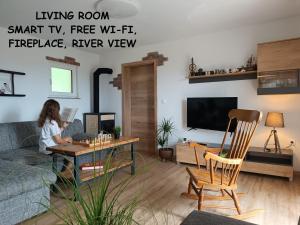a young girl sitting at a table in a living room at RELAX HOUSE Kolpa view Podzemelj in Gradac