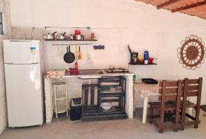 a kitchen with a white refrigerator and a table at Casinha Guiné MorroSP in Morro de São Paulo