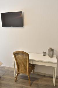 a white desk with a chair and a television on a wall at Beira Mar Loft in Aveiro
