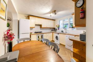a kitchen with a table and chairs and a refrigerator at 4 bed home 3 mins from harbour + sandy beach in Kent