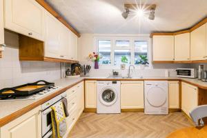 a kitchen with white cabinets and a washer and dryer at 4 bed home 3 mins from harbour + sandy beach in Kent