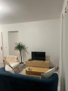 a living room with a blue couch and a tv at EKR Résidence - Terrasse Privée 1 in Carbon-Blanc
