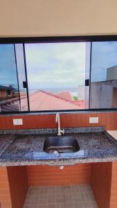 a bathroom counter with a sink and a window at Moradias Maestrelli in Guaratuba