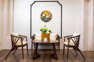 a table with two chairs and a vase with flowers on it at 2 Indochine Design Apartment - Hanoi Old Quarter in Hanoi