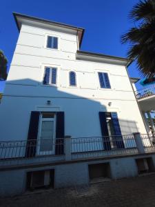 a white building with a balcony and a palm tree at Marina Azzurra VistaMare - HiTuscany in Marina di Campo