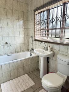 Un baño con inodoro, lavabo y bañera. en The Herby Taylor Guest House, en Vereeniging