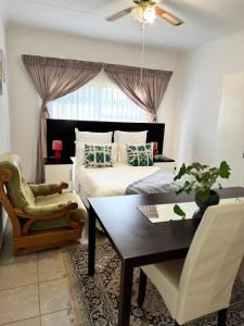 Un dormitorio con una cama, una mesa y una silla. en The Herby Taylor Guest House, en Vereeniging 20 fotos más
