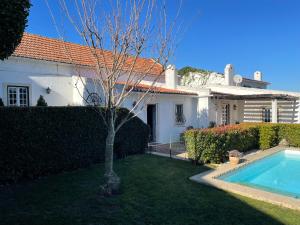 a white house with a tree and a swimming pool at Villa das Vinhas in Aldeia Galega da Merceana