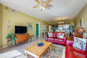 sala de estar con muebles de color rojo y TV de pantalla plana en Emerald Isle 0107, en Pensacola Beach