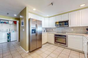 Una cocina con gabinetes blancos y un refrigerador de acero inoxidable. en Emerald Isle 0107, en Pensacola Beach