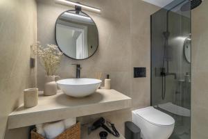 a bathroom with a sink and a toilet and a mirror at Fly & Stay in Artemida