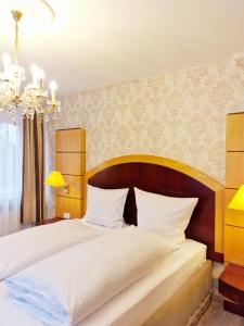 a bedroom with a large bed and a chandelier at Pension Pale' Bach in Bad Hersfeld