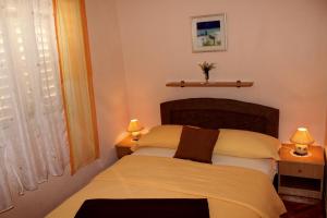 a bedroom with a bed with two lamps and a window at Apartment Madlena in Brodarica