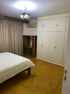 a bedroom with a bed and white cabinets and wooden floors at Z m abartment hotel in Giza
