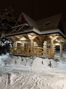 una cabaña de madera en la nieve por la noche en Domek w górach, en Kościelisko