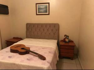 a guitar laying on a bed in a bedroom at Casa espaçosa a 300m do mar in Piçarras