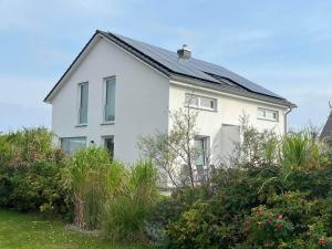 a white house with a black roof at HausLIEBLINGSPLATZ - am Meer - Luxus Villa mit 4 Schlafzimmern, 3 Badezimmern Sauna, Kamin, Weber-Grill und Wallbox in Dranske
