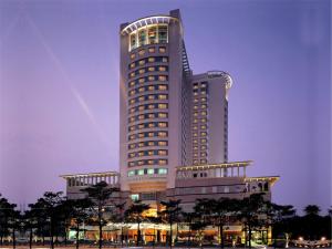 um grande edifício alto com árvores em frente em Shantou Junhua Haiyi Hotel em Shantou