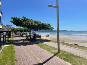 a sidewalk next to a beach with a pole at Aconchego pé na sand PierHardRock Area nobre in Perequê