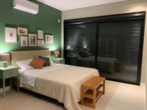 a bedroom with a bed with green walls and a window at Cobertura pôr-do-sól com jacuzzi in Bombinhas