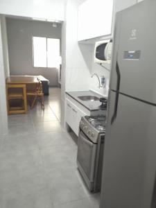 eine Küche mit einem Herd, einer Spüle und einem Kühlschrank in der Unterkunft Studio na Biquinha em São Vicente in São Vicente